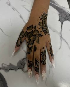 a woman's hand with black and white tattoos on her left arm, holding onto a marble counter top