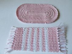 two pink and white crocheted items sitting on top of a table