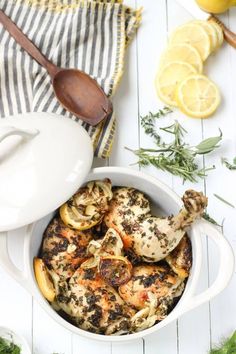 a bowl filled with food next to lemons and herbs