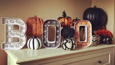 the word boo spelled out with pumpkins and gourds on top of a dresser