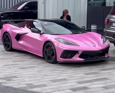 a pink sports car parked in front of a building