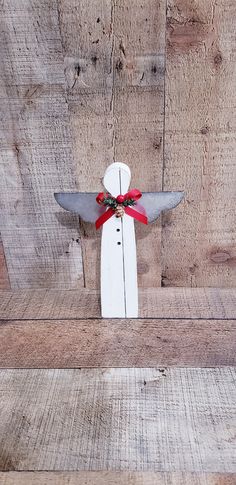 a small wooden angel with red ribbon on it's wings