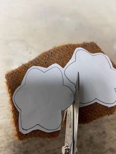 a pair of scissors cutting out paper clouds on a piece of fabric with felt backings