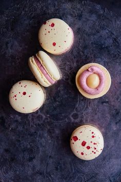 three macaroons with pink icing and red splatters on the top