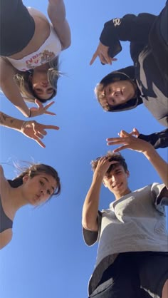 four people standing in a circle with their hands up