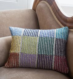 a striped pillow sitting on top of a brown couch next to a wooden arm chair