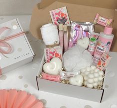 an open box with various items in it sitting on a table next to a pink fan