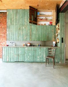 an old kitchen with green painted cabinets and a wooden chair in the middle of the room