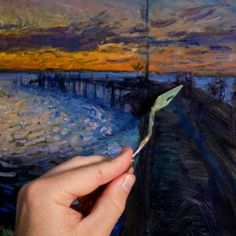 a person is holding a paintbrush in front of a painting