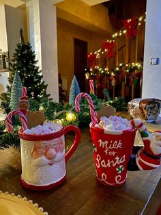 two mugs decorated with candy canes and marshmallows on a table