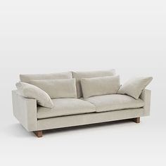 a white couch with two pillows on it's back and one arm folded up