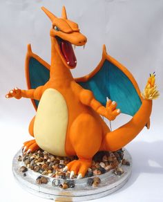 an orange and white dragon figurine sitting on top of some gravel with it's mouth open