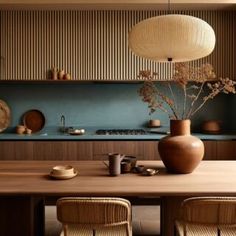 a wooden table topped with a vase filled with flowers sitting next to a kitchen counter