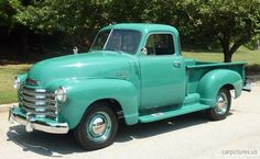 an old green truck is parked on the street