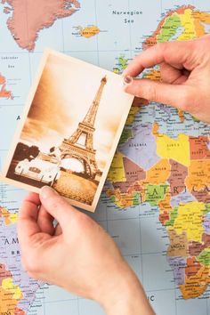 two hands holding up a small postcard with the eiffel tower on it