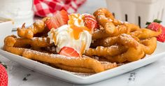 a white plate topped with waffles covered in whipped cream and strawberries