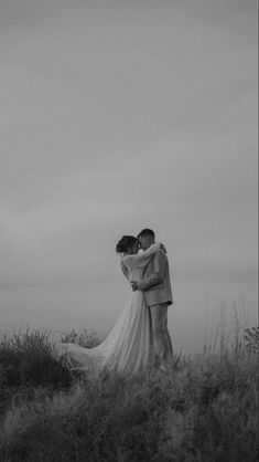 black and white photo of bride and groom embracing in the middle of a grassy field