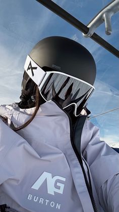 a person wearing a helmet and goggles on top of a ski lift with the sky in the background