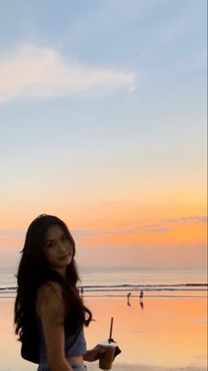 a woman standing on top of a beach next to the ocean holding a knife and fork