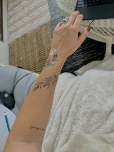 a woman's arm with a tattoo on it and a laptop in the background