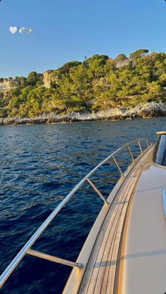 the back end of a boat traveling along a body of water with trees in the background