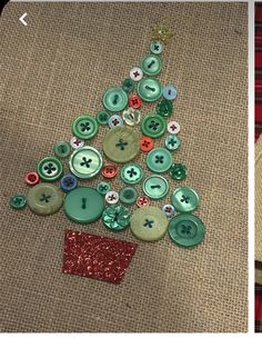 a christmas tree made out of buttons sitting on top of a piece of fabric next to scissors