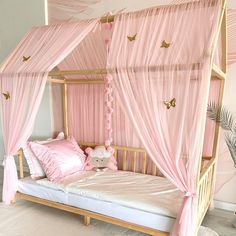 a pink canopy bed with white sheets and pillows