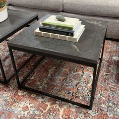 a coffee table with two books on it and a couch in the backround