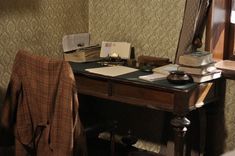 an old desk with books, papers and a blanket on it next to a window