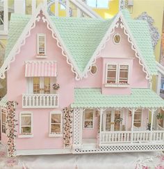 a pink doll house with green roof and white balcony