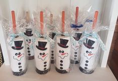 there are four decorated wine bottles in the shape of snowmen with hats on them