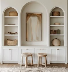 two stools in front of white built - in shelves with baskets on each shelf