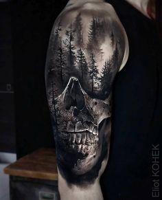 a man's arm with a skull and trees on it