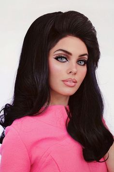 Makeup artist Jackie Wyers has transformed herself into a 1968 version of Priscilla Presley. She is wearing a big black wig, has light blue contacts and is wearing a barbie pink outfit. Priscilla Presley 60s, Priscilla Presley Hair, 60s Makeup Tutorial, Priscilla Presley Wedding, Haley Modern Family, 60’s Makeup, 1960s Makeup, 60s Makeup, 60s Hair