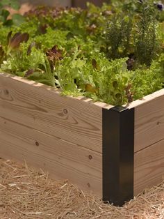 a wooden planter filled with lettuce and other vegetables on top of straw