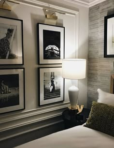 a bedroom with pictures on the wall and a bed in front of it that has a lamp next to it