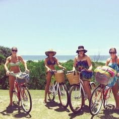 three women in bikinis and hats on bicycles