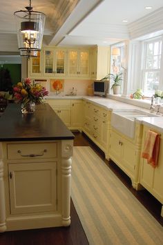 a large kitchen with yellow cabinets and black counter tops is pictured in this image, there are flowers on the island