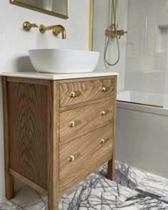 a white sink sitting on top of a wooden cabinet in a bathroom next to a bath tub