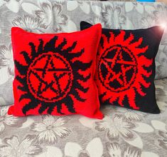 two red and black pillows sitting on top of a couch next to each other,