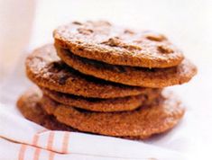 a stack of cookies sitting on top of a white napkin next to a cup of coffee