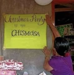 a woman reaching up for a christmas party sign