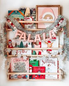 a wooden shelf filled with books and christmas decorations on top of a wall next to a white wall