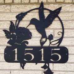 a metal sign on the side of a brick building with a bird and flower design