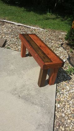 a wooden bench sitting on top of a cement slab next to a grass covered field