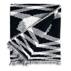 a black and white throw with fringes on it's edges, in the shape of an abstract design