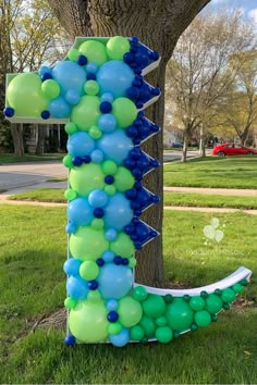 the letter i made out of balloons is in front of a tree and grass field