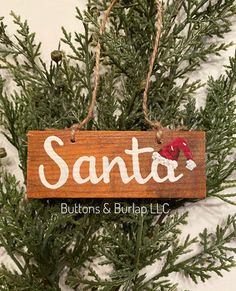 a christmas ornament hanging from a tree with the word santa written on it