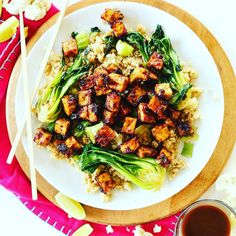 a white plate topped with tofu and broccoli next to chopsticks