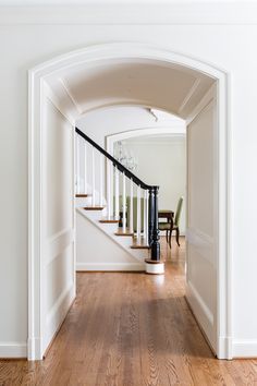 an archway leading to a dining room and living room with hardwood floors, white walls and wood flooring